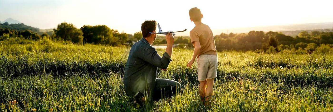 Father and son flying a toy plane in the meadows of Kasara